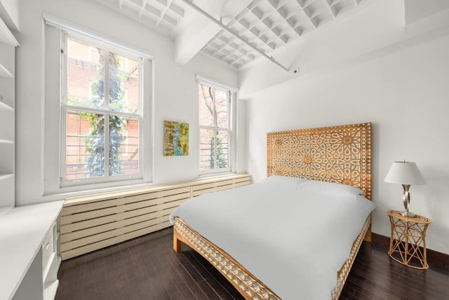 bedroom featuring dark hardwood / wood-style flooring, beam ceiling, and multiple windows