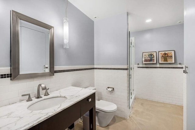 bathroom with vanity, a shower with shower door, tile walls, and toilet