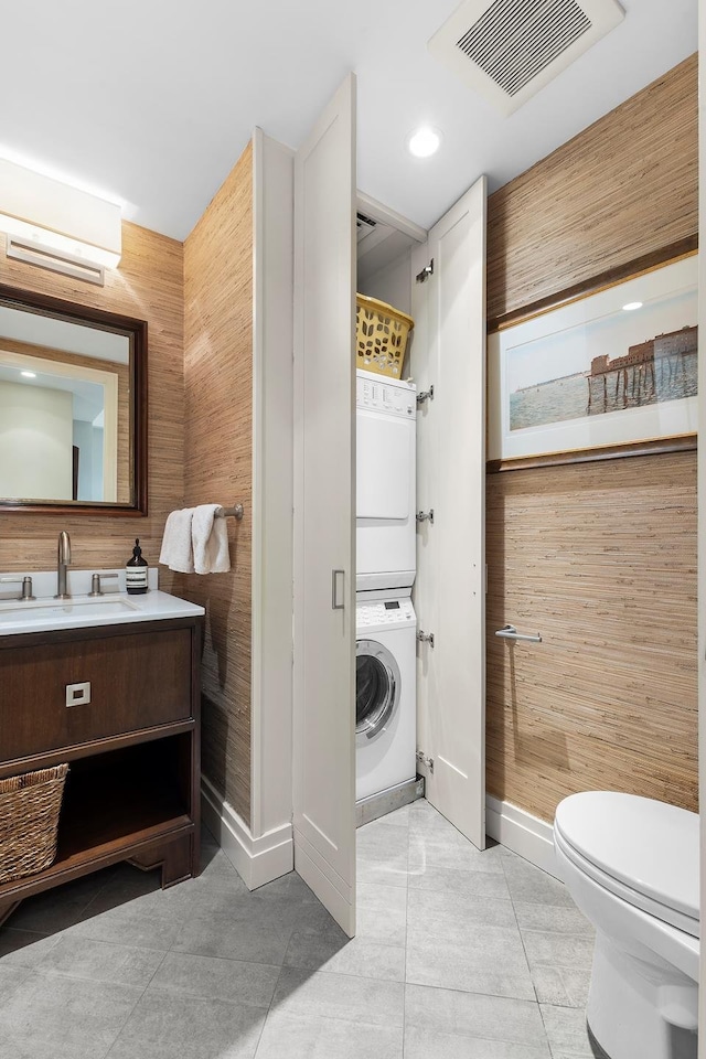 full bath with toilet, stacked washer and dryer, vanity, visible vents, and a wall mounted AC