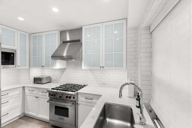 kitchen featuring stainless steel appliances, a sink, ventilation hood, backsplash, and light stone countertops