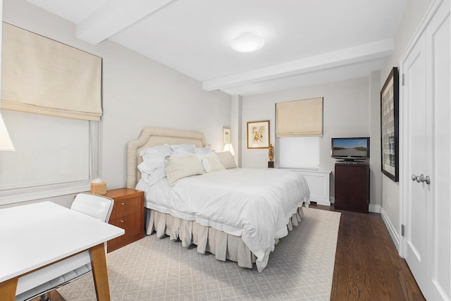 bedroom featuring wood finished floors, beam ceiling, and baseboards