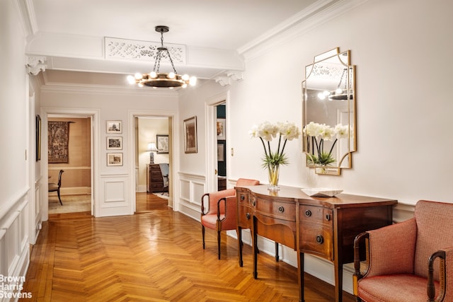 corridor with crown molding, a decorative wall, a notable chandelier, and wainscoting