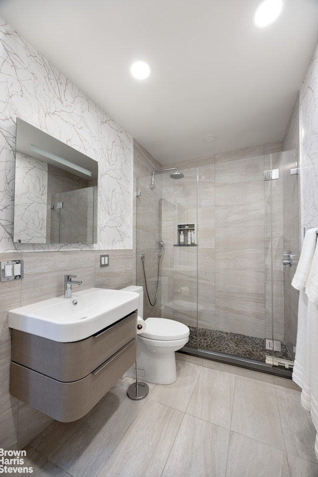 bathroom with toilet, tile walls, a stall shower, and vanity