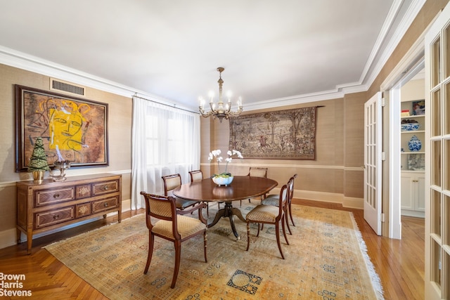 dining space with a notable chandelier, baseboards, visible vents, and ornamental molding