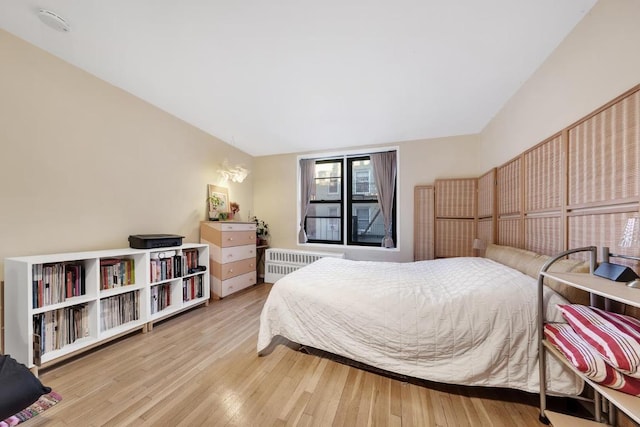 bedroom with radiator heating unit and hardwood / wood-style floors