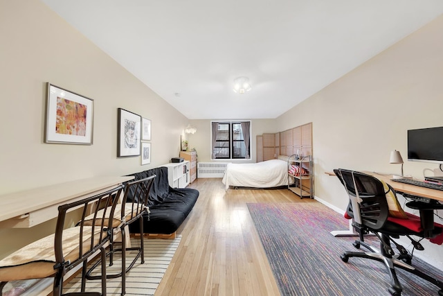 bedroom with light wood-style floors, baseboards, and radiator heating unit