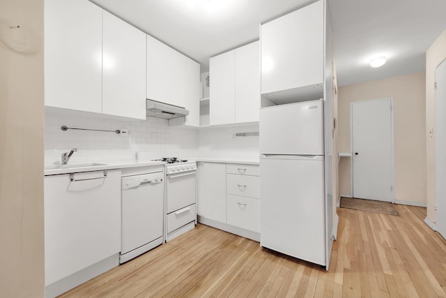 kitchen with white appliances, light countertops, under cabinet range hood, white cabinetry, and a sink