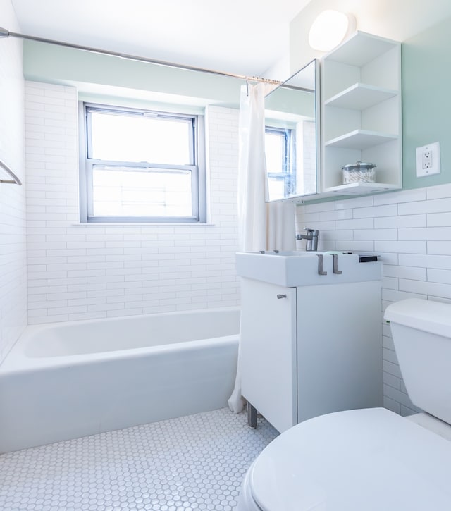full bathroom with tile walls, vanity, shower / tub combo, and toilet