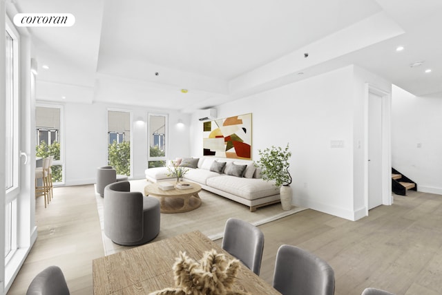 living room featuring light hardwood / wood-style floors, a raised ceiling, and a wall unit AC