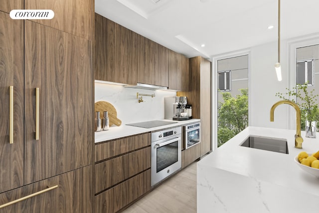 kitchen with light hardwood / wood-style flooring, sink, light stone counters, oven, and black electric stovetop