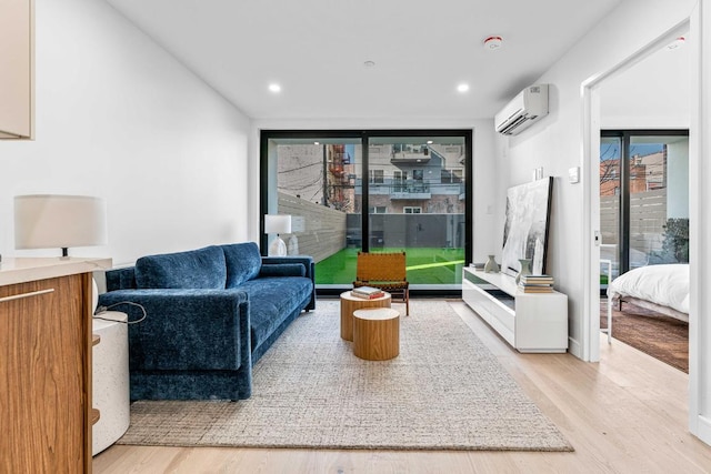 sitting room with floor to ceiling windows, a wall unit AC, and light hardwood / wood-style flooring