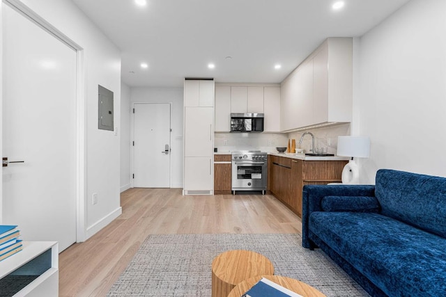 kitchen featuring white cabinetry, light hardwood / wood-style flooring, electric panel, high end stainless steel range oven, and backsplash