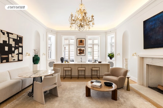 living area featuring ornamental molding, a premium fireplace, and a chandelier