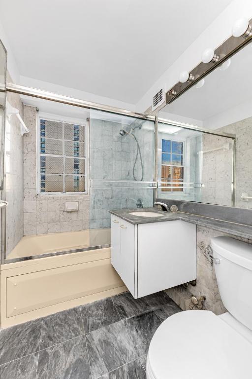 full bathroom featuring vanity, combined bath / shower with glass door, and toilet