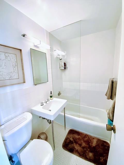 full bathroom with tiled shower / bath, sink, tile patterned floors, and toilet