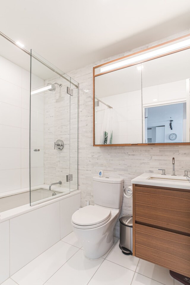 full bathroom featuring tile walls, tile patterned flooring, tiled shower / bath combo, vanity, and toilet