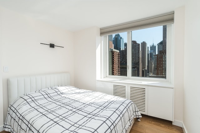 bedroom featuring radiator heating unit and light wood-type flooring