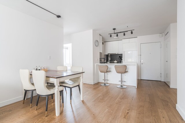 dining space with rail lighting and light wood-type flooring