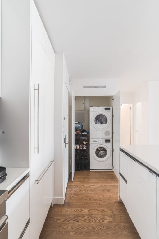 clothes washing area featuring stacked washer and clothes dryer and dark hardwood / wood-style flooring