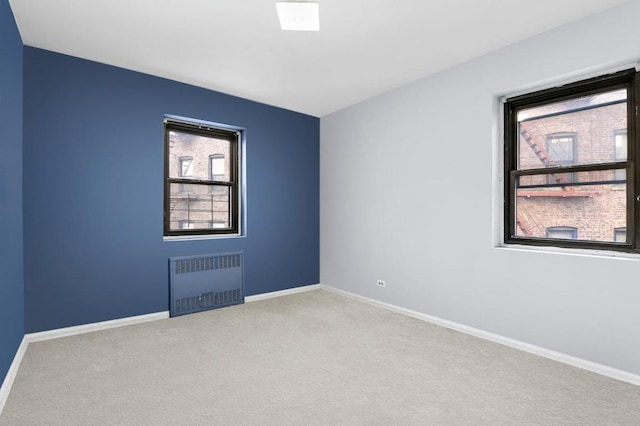 unfurnished room with radiator and light carpet