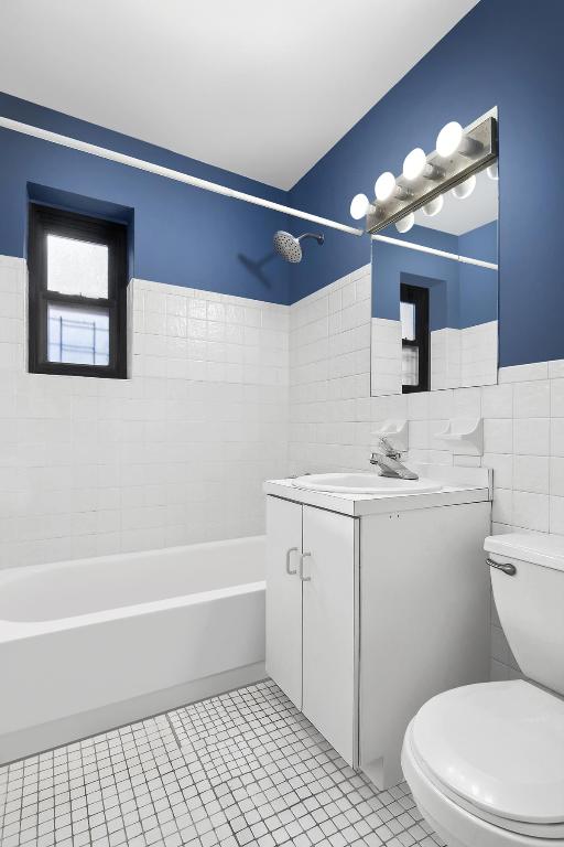 full bathroom featuring tile walls, tile patterned flooring, vanity, toilet, and tiled shower / bath