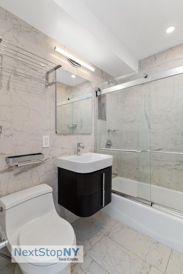 bathroom with vanity, toilet, marble finish floor, tile walls, and combined bath / shower with glass door
