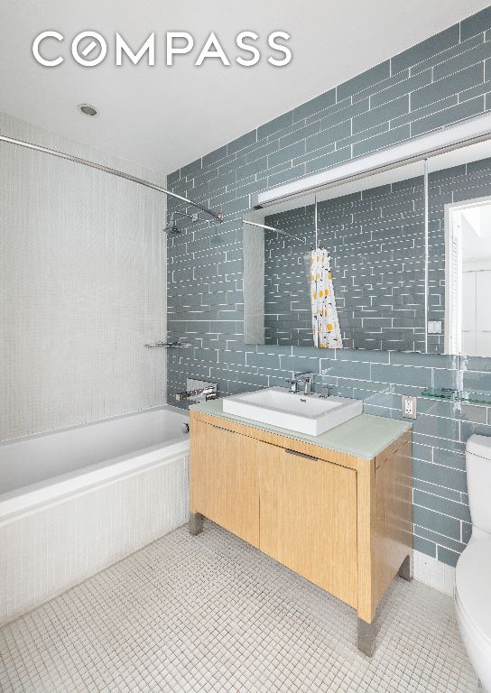 full bathroom featuring tile walls, tile patterned flooring, vanity, tiled shower / bath, and toilet