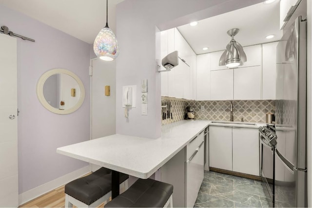 kitchen with white cabinetry, sink, a kitchen bar, hanging light fixtures, and kitchen peninsula