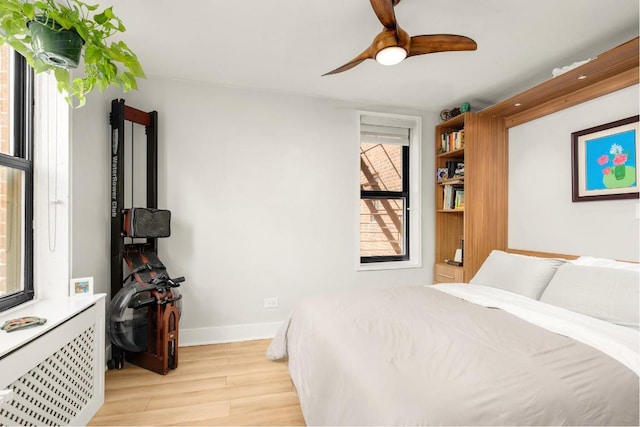 bedroom with radiator heating unit, light hardwood / wood-style flooring, and ceiling fan