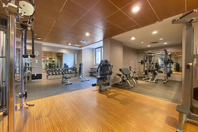 workout area featuring visible vents, a paneled ceiling, baseboards, and wood finished floors