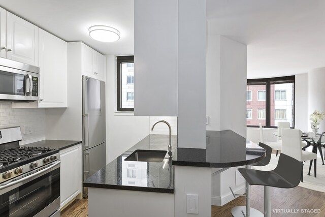 kitchen with appliances with stainless steel finishes, sink, a wealth of natural light, and white cabinets