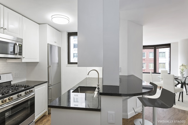 330 E 38th St Unit 8E, New York City, NY 10016 - kitchen with stainless steel appliances, a sink, white cabinets, backsplash, and wood finished floors