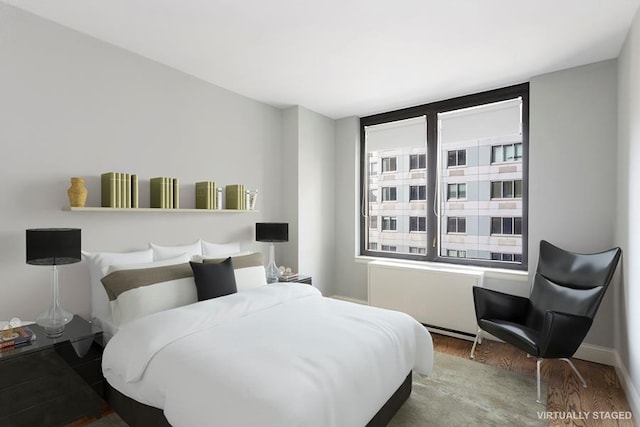 bedroom with wood finished floors and radiator heating unit