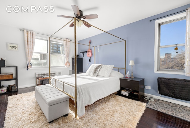 bedroom with baseboards, ceiling fan, radiator heating unit, and wood finished floors