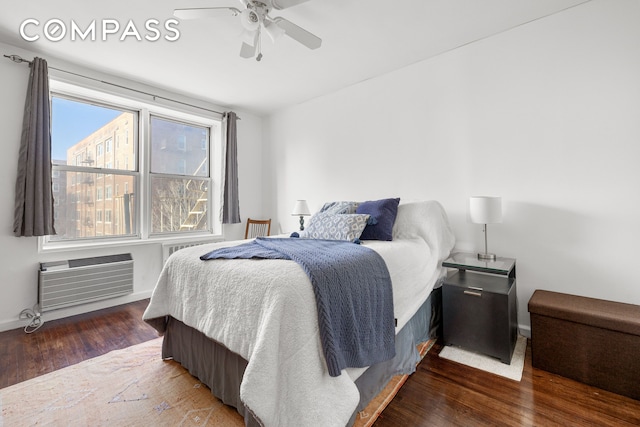 bedroom with ceiling fan, baseboards, wood finished floors, and a wall mounted AC