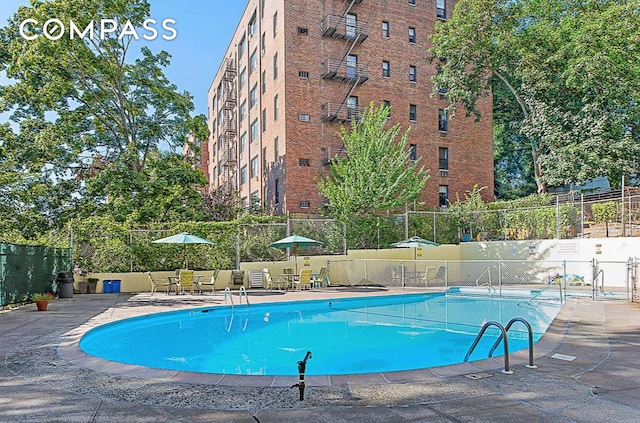 view of swimming pool featuring a patio area and fence