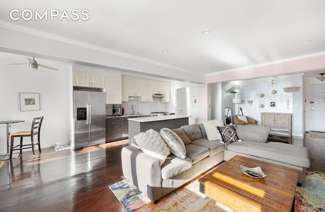 living room with ceiling fan, ornamental molding, dark hardwood / wood-style flooring, and sink