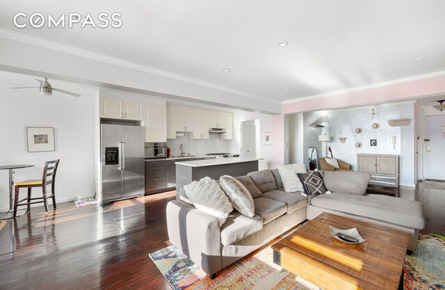 living area featuring ceiling fan, recessed lighting, dark wood-type flooring, baseboards, and crown molding