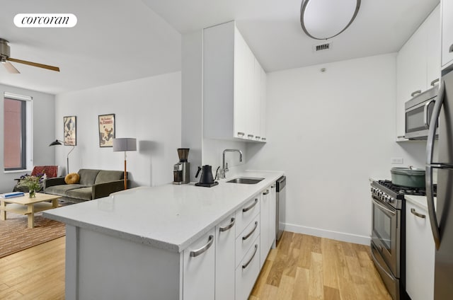 kitchen featuring light wood-type flooring, appliances with stainless steel finishes, sink, and white cabinets