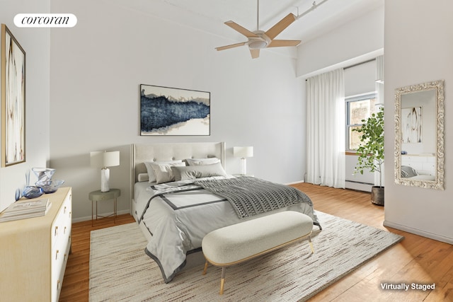 bedroom with light hardwood / wood-style floors and a baseboard heating unit