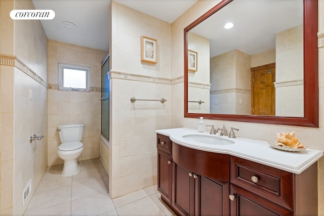 full bathroom with bath / shower combo with glass door, toilet, tile walls, vanity, and tile patterned floors