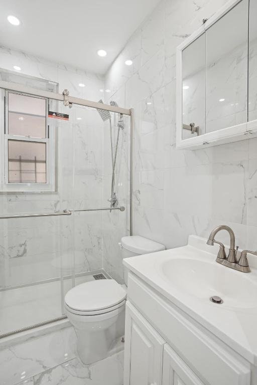 bathroom with vanity, tile walls, an enclosed shower, and toilet