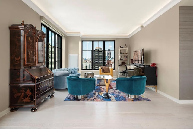 living area featuring baseboards, ornamental molding, and wood finished floors