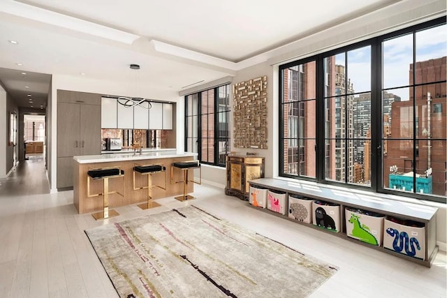 interior space with a center island, light hardwood / wood-style floors, hanging light fixtures, and a breakfast bar area