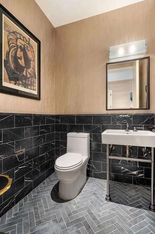 bathroom featuring sink, tile walls, and toilet