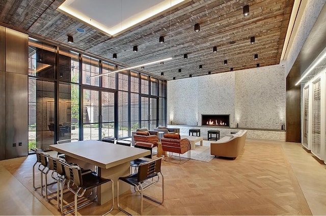 interior space with a fireplace, light parquet flooring, a towering ceiling, and brick ceiling