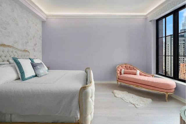 bedroom with crown molding, baseboards, wallpapered walls, and wood finished floors