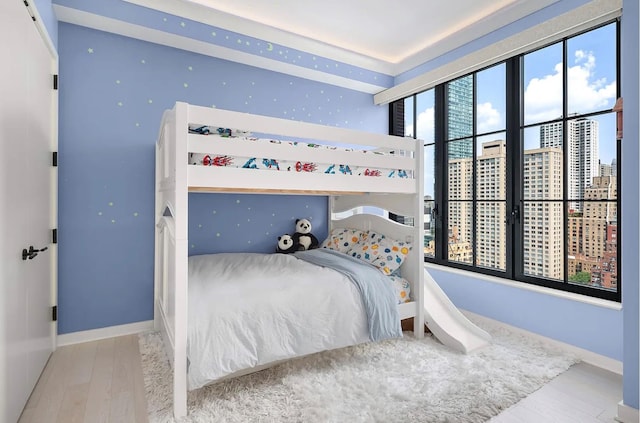 bedroom featuring a view of city, baseboards, and wood finished floors