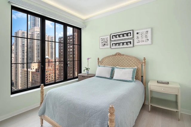 bedroom with baseboards, a city view, and wood finished floors