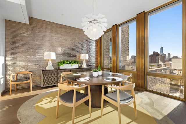 dining space with hardwood / wood-style floors and brick wall